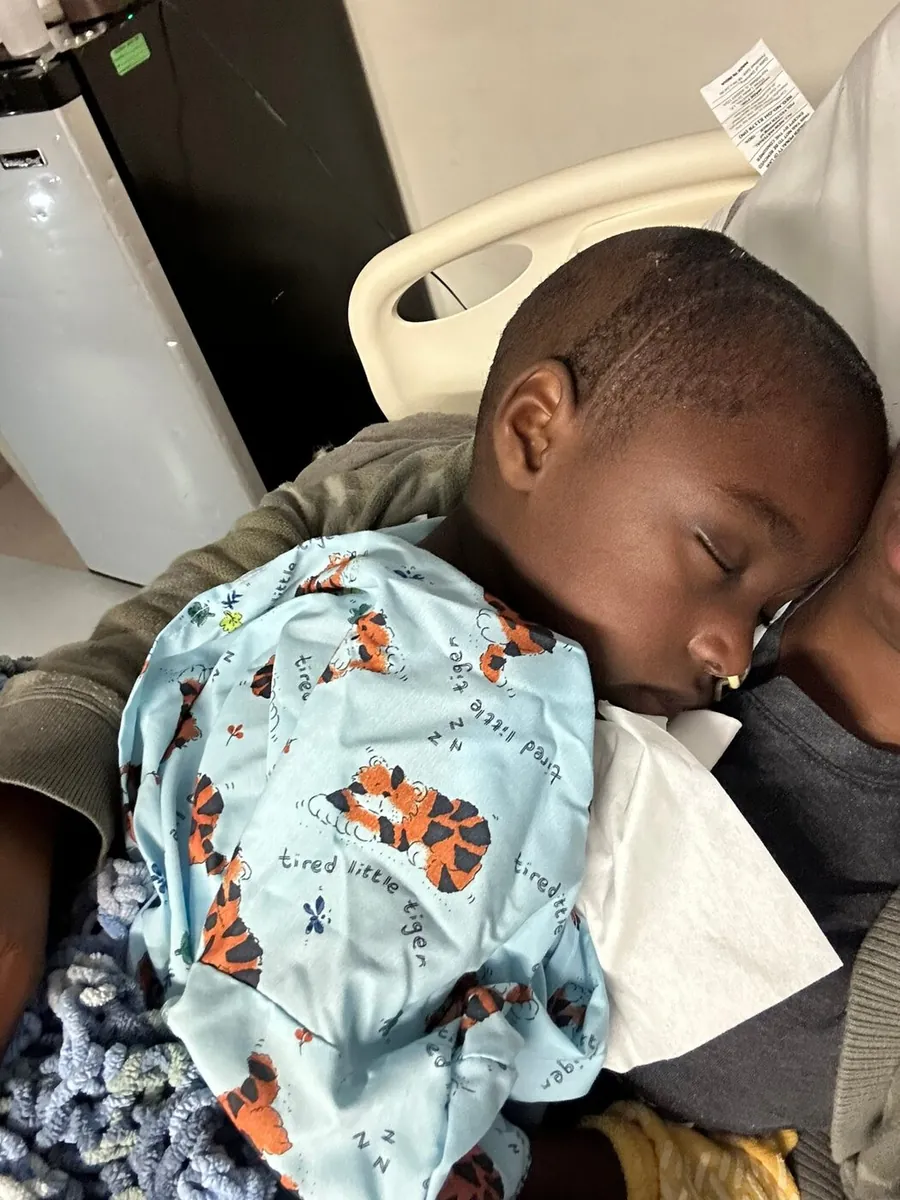 Justus asleep on his parent's shoulder in the hospital.
